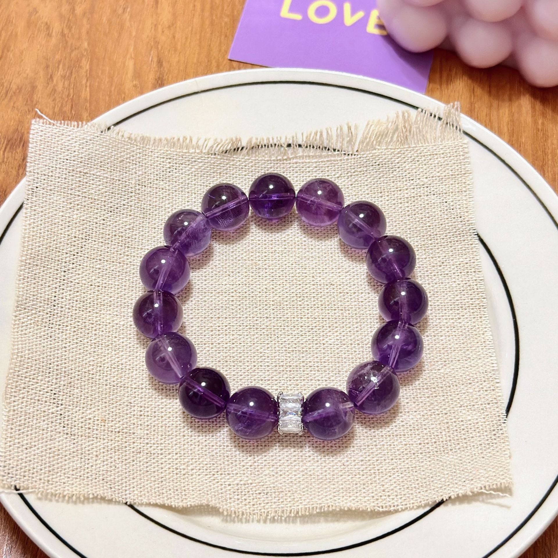 Natural amethyst crystal bead bracelet displayed on fabric showing purple healing gemstone jewelry